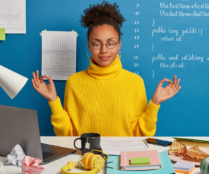 Woman with closed eyes focusing at a messy desk.