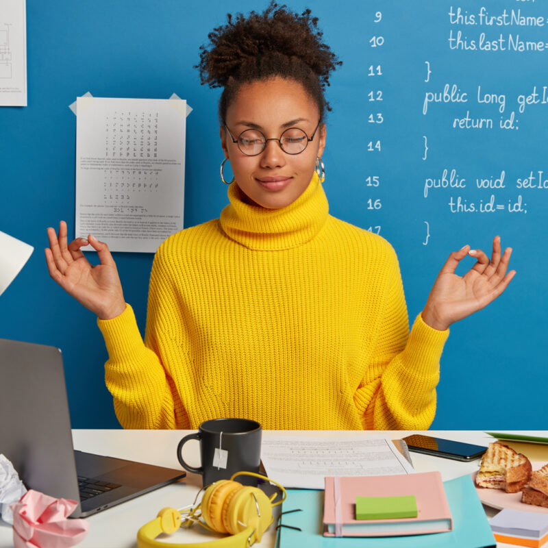 Woman with closed eyes focusing at a messy desk.