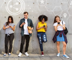 People standing along a wall scrolling social media